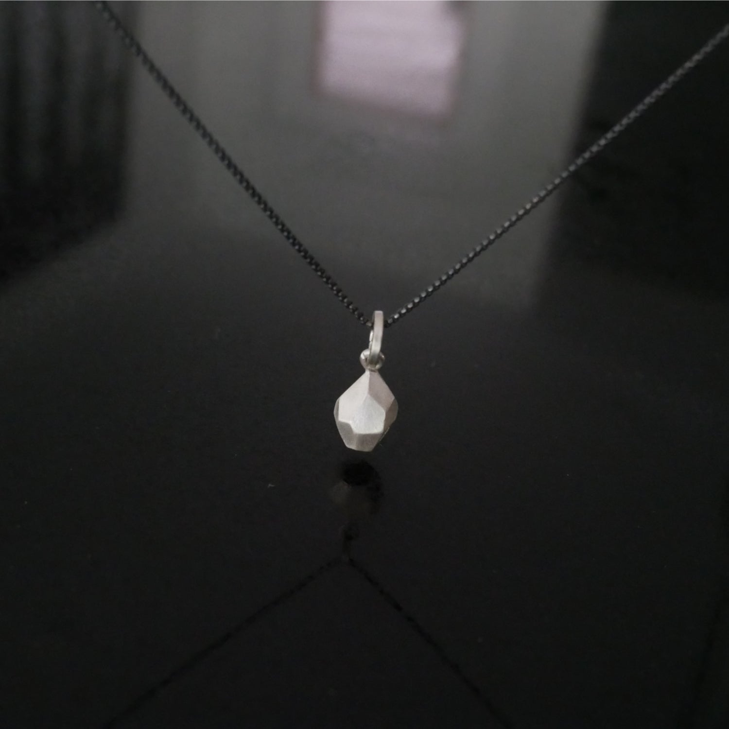 Silver necklace with a faceted pendant.