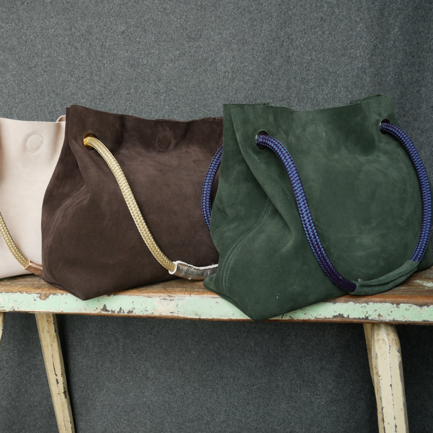 green suede bag with navy blue cord handle